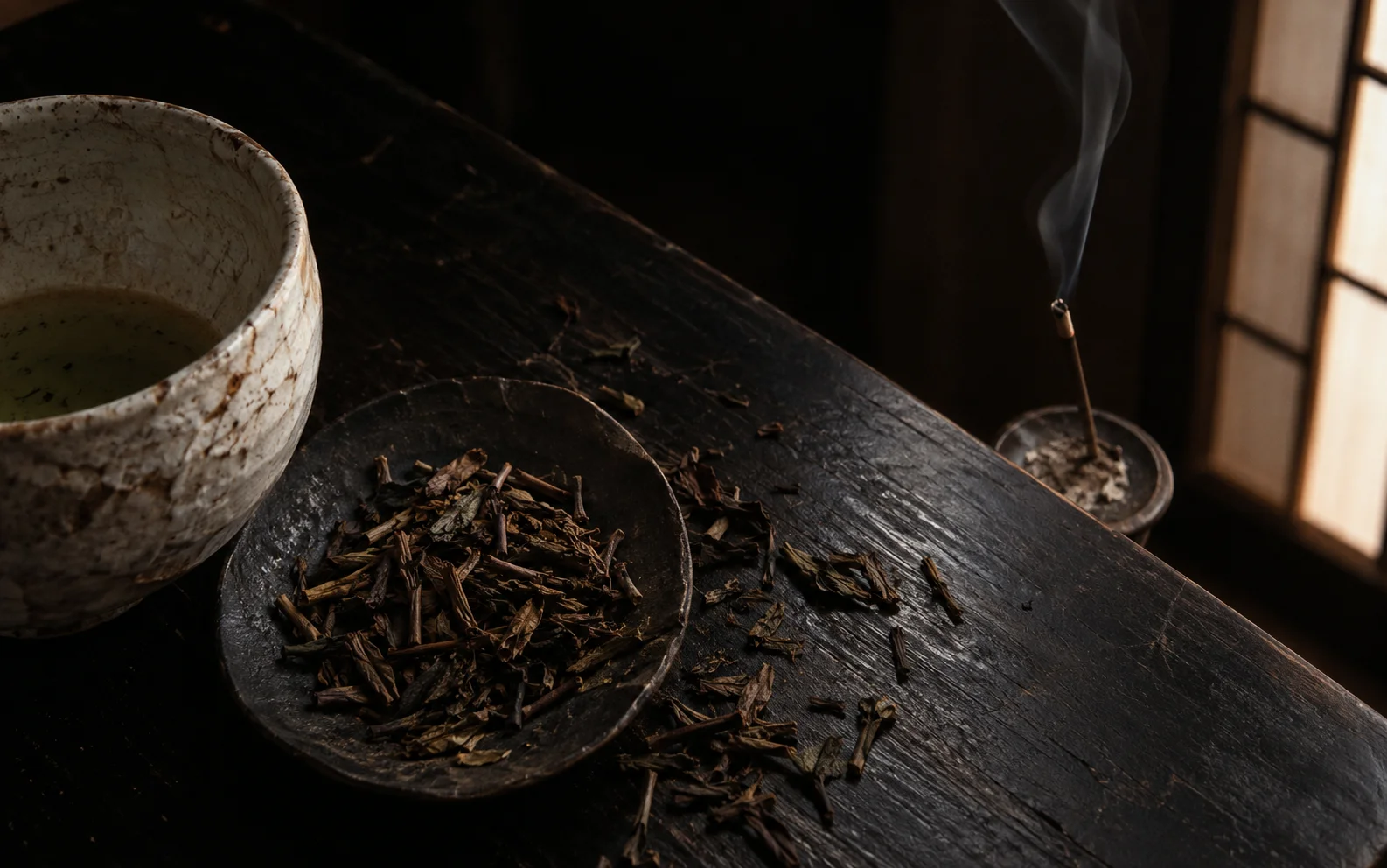 黒い机の上の茶葉と白い茶碗